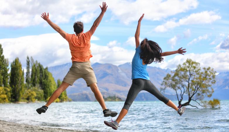 Couple jumping for joy in front of a lake view